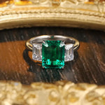 Load image into Gallery viewer, Emerald-cut green gemstone ring flanked by two rectangular diamonds.
