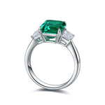 Load image into Gallery viewer, Emerald-cut green gemstone ring with diamond side stones set in white metal.
