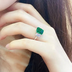 Load image into Gallery viewer, Emerald-cut green gemstone ring with diamond accents on a silver band.
