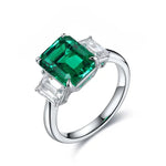 Load image into Gallery viewer, Silver ring featuring a prominent emerald-cut green gemstone flanked by two smaller clear stones.
