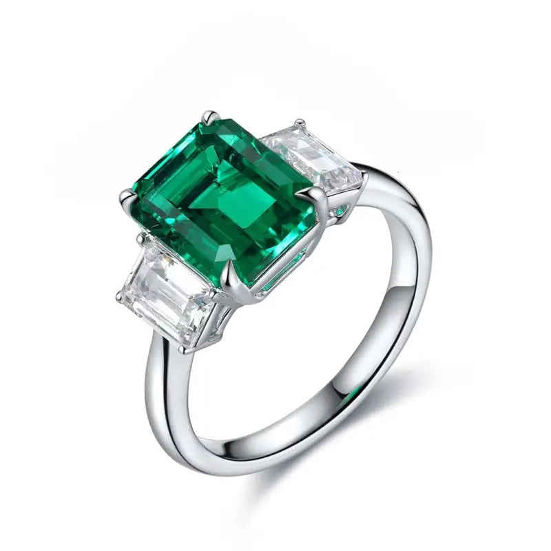 Silver ring featuring a prominent emerald-cut green gemstone flanked by two smaller clear stones.