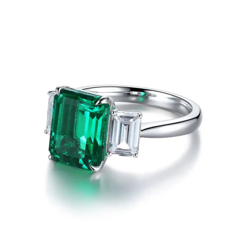 Emerald-cut gemstone ring with a vibrant green center stone and side diamonds.