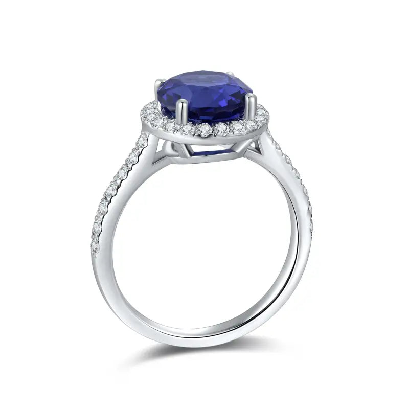 Elegant silver ring featuring a deep blue oval gemstone surrounded by small diamonds.