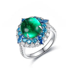 Load image into Gallery viewer, Ornate silver ring featuring a vibrant green gemstone surrounded by blue and clear stones.
