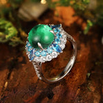 Load image into Gallery viewer, Ornate ring featuring a green gemstone surrounded by blue and clear stones in a silver setting.
