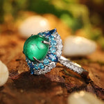 Load image into Gallery viewer, Ornate ring featuring a prominent green gemstone surrounded by blue and clear stones.
