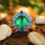 Load image into Gallery viewer, Ornate ring featuring a vibrant green gemstone surrounded by smaller blue stones.
