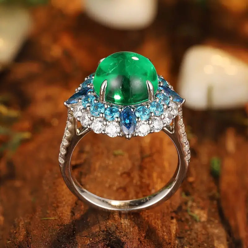 Ornate silver ring featuring a prominent green gemstone surrounded by blue and clear stones.