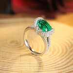 Load image into Gallery viewer, Elegant silver ring featuring a pear-shaped emerald surrounded by diamonds.
