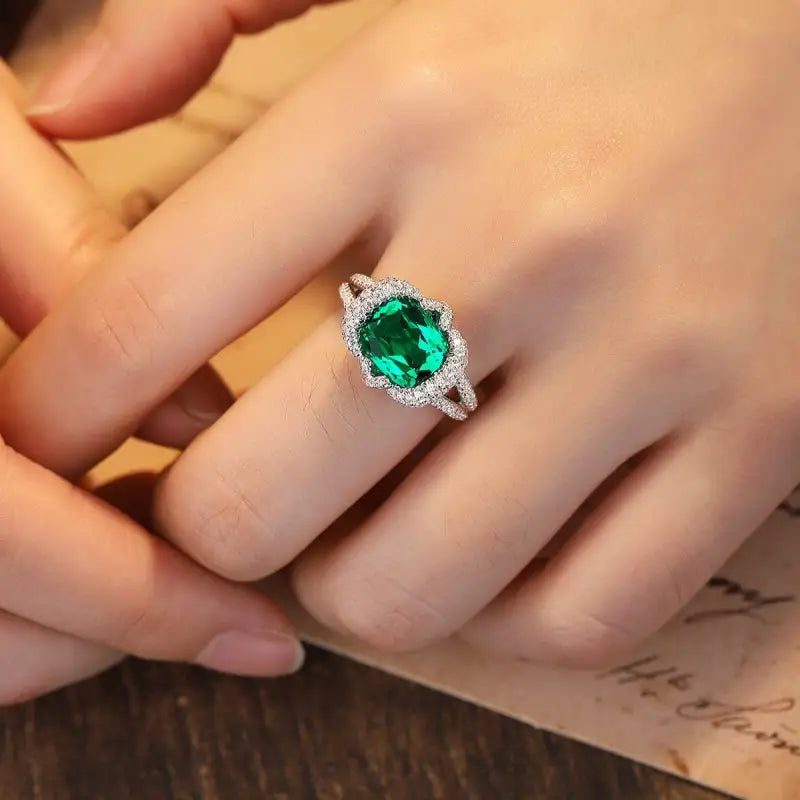 Emerald and diamond ring on a person’s finger.