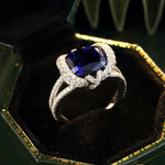 Load image into Gallery viewer, Elegant ring featuring a deep blue sapphire surrounded by diamonds in a white gold or platinum setting.
