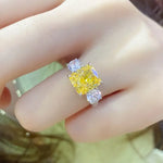 Load image into Gallery viewer, Yellow diamond ring flanked by two white diamonds on a gold band.
