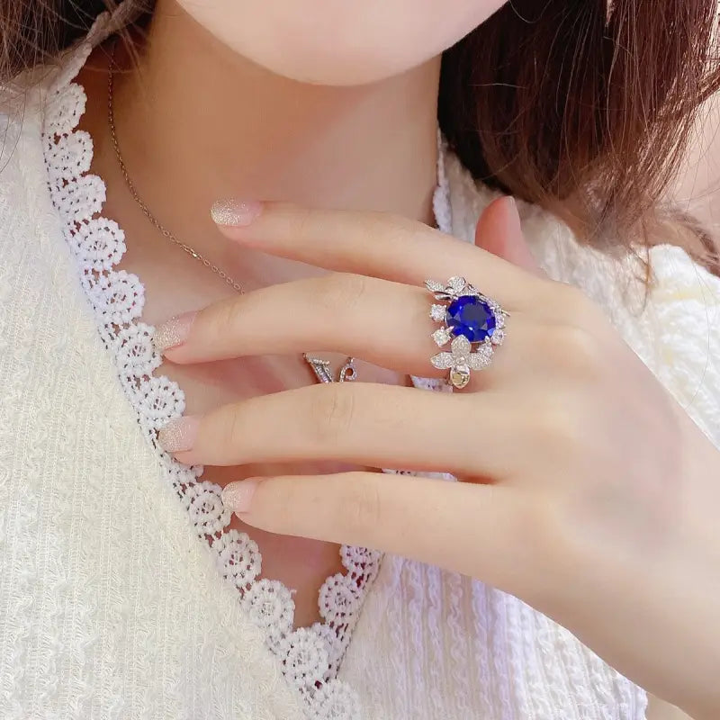 Ornate ring featuring a central blue gemstone surrounded by smaller clear stones.