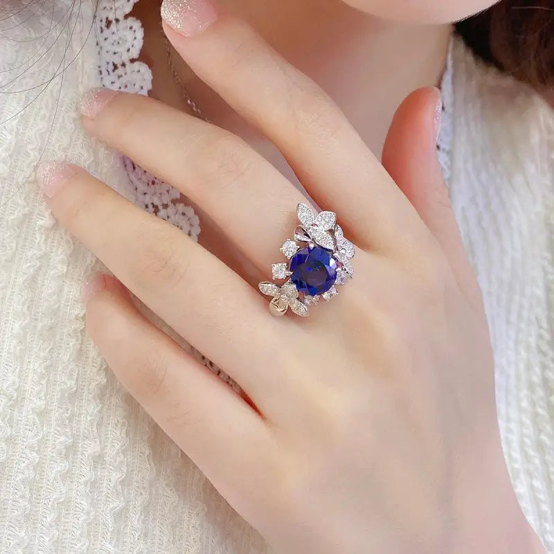 Ornate ring featuring a central blue gemstone surrounded by smaller clear stones.