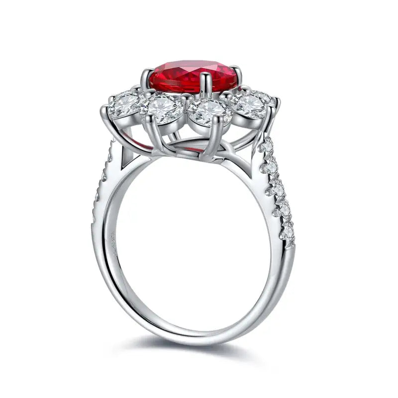 Ornate silver ring featuring a central red gemstone surrounded by clear diamonds.