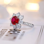 Load image into Gallery viewer, Elegant ring featuring a vibrant red gemstone surrounded by clear diamonds in a floral-like setting.
