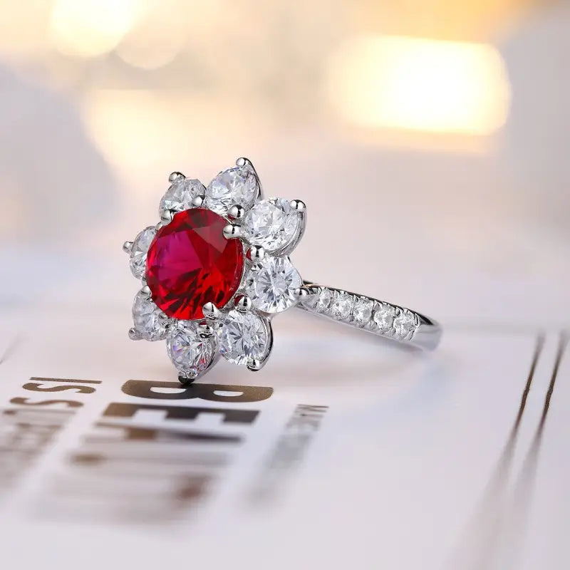 Elegant ring featuring a vibrant red gemstone surrounded by clear diamonds in a floral-like setting.