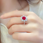 Load image into Gallery viewer, Ruby and diamond floral-style ring on a finger.
