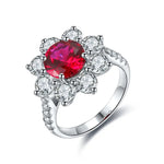 Load image into Gallery viewer, Ornate silver ring featuring a vibrant red gemstone surrounded by clear diamonds in a floral design.
