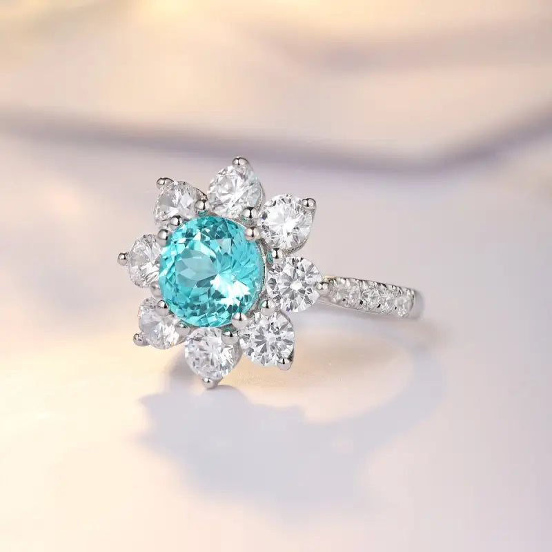 Ornate ring featuring a central aquamarine gemstone surrounded by diamond accents in a floral-inspired setting.