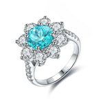 Load image into Gallery viewer, Ornate silver ring featuring a central turquoise gemstone surrounded by clear diamonds in a floral design.
