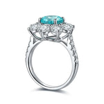 Load image into Gallery viewer, Elegant silver ring featuring a central teal gemstone surrounded by clear diamonds.
