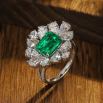 Load image into Gallery viewer, Ornate ring featuring a central emerald-cut emerald surrounded by pear-shaped diamonds.
