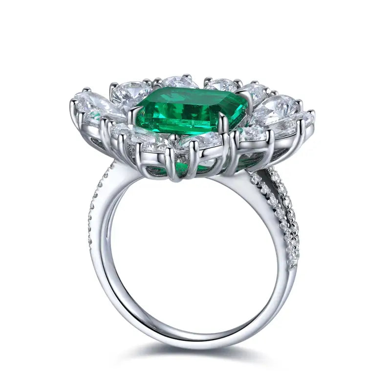 Ornate silver ring featuring a central emerald-cut green gemstone surrounded by clear diamonds.