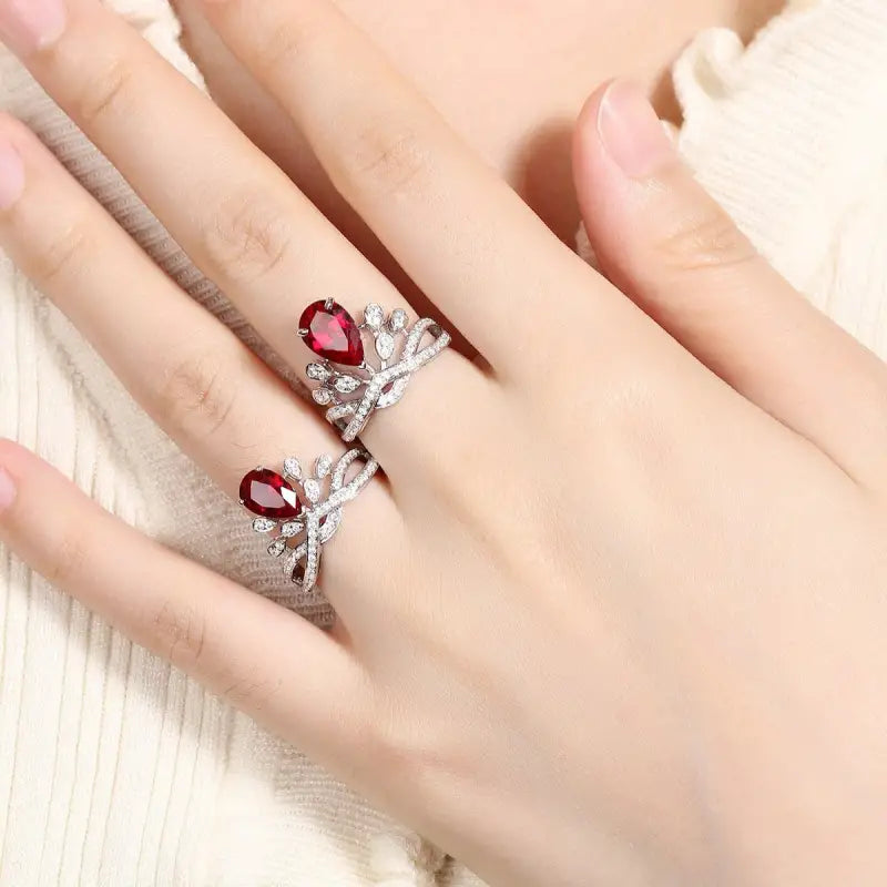 Elegant ring featuring two red gemstones and diamond-like accents in a butterfly-inspired design.