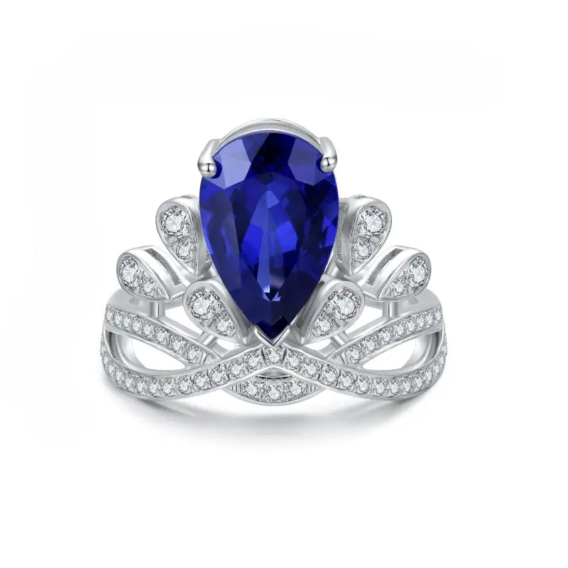 Ornate silver ring featuring a pear-shaped blue gemstone surrounded by diamond accents.