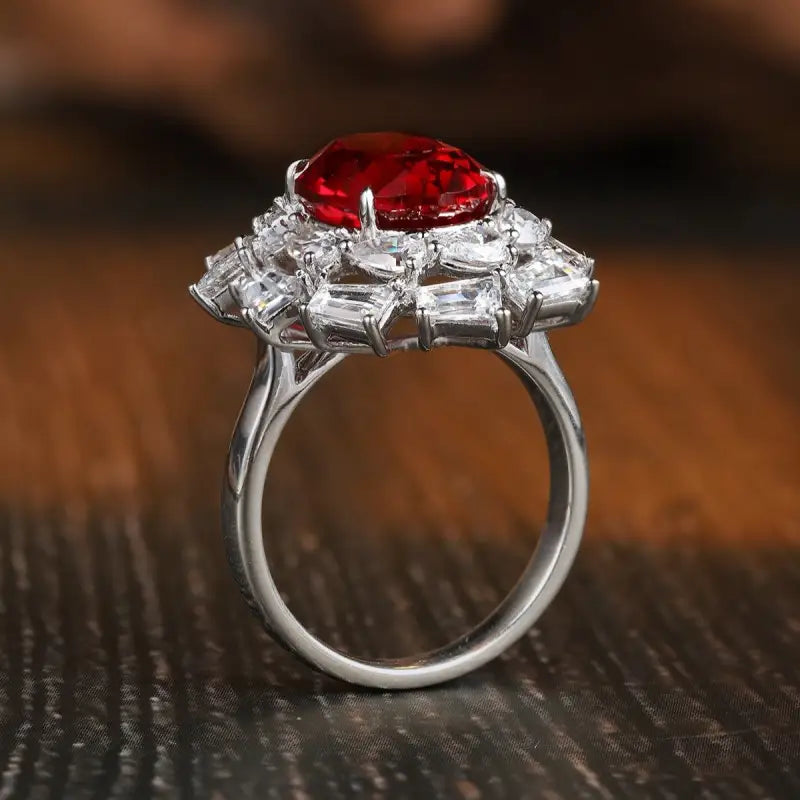 Ornate silver ring featuring a central red gemstone surrounded by clear diamonds.