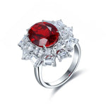 Load image into Gallery viewer, Ornate silver ring featuring a prominent oval-cut red gemstone surrounded by smaller white gemstones.
