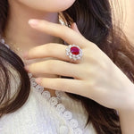 Load image into Gallery viewer, Ornate ring featuring a prominent red gemstone surrounded by smaller clear stones.
