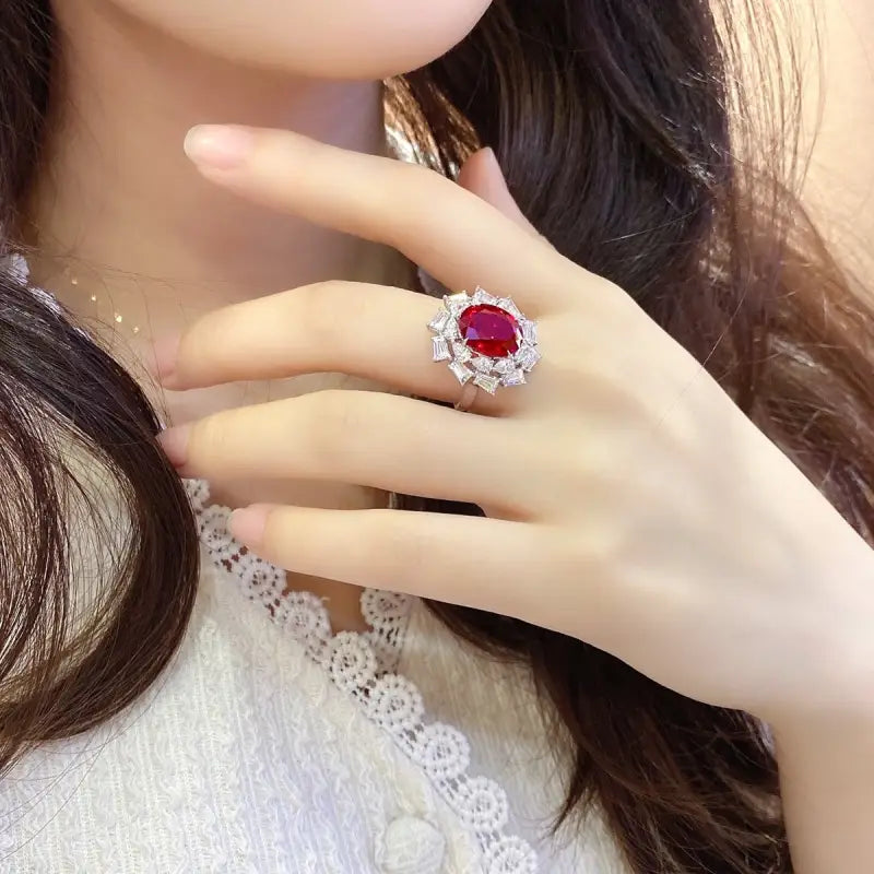 Ornate ring featuring a prominent red gemstone surrounded by smaller clear stones.