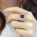 Load image into Gallery viewer, Ornate ring featuring a vibrant red gemstone surrounded by smaller clear stones.
