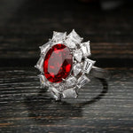 Load image into Gallery viewer, Ornate ring featuring a vibrant red gemstone surrounded by clear diamonds.
