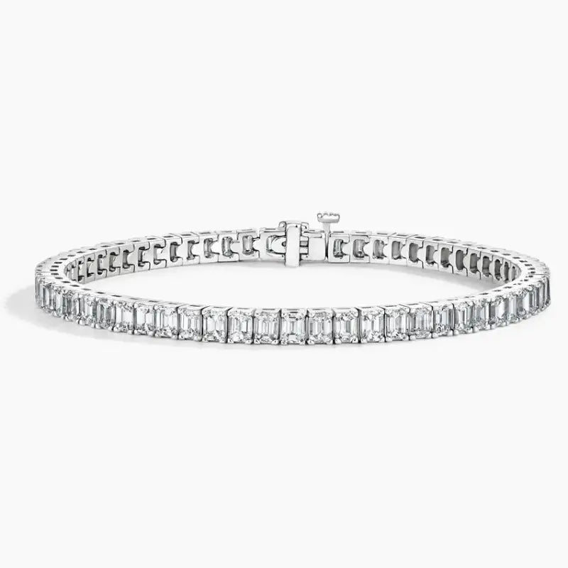 Diamond tennis bracelet with emerald-cut stones set in a white metal.