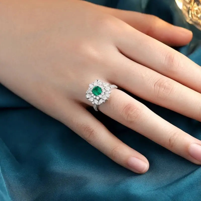 Emerald and diamond ring on a person’s finger.