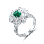 Load image into Gallery viewer, Ornate silver ring featuring a central emerald surrounded by diamond accents in a floral design.
