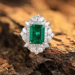 Load image into Gallery viewer, Emerald-cut green gemstone ring surrounded by diamonds in a white metal setting.
