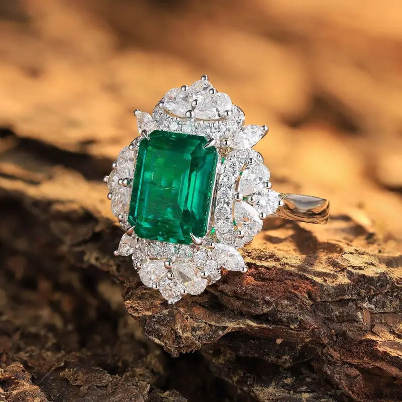 Emerald-cut green gemstone ring surrounded by diamonds in a white gold or platinum setting.