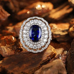 Load image into Gallery viewer, Ornate ring featuring a deep blue sapphire surrounded by diamonds in a white gold or platinum setting.
