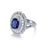 Load image into Gallery viewer, Ornate silver ring featuring a deep blue sapphire surrounded by diamonds.
