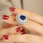 Load image into Gallery viewer, Ornate ring featuring a central blue gemstone surrounded by diamonds in a double halo setting.
