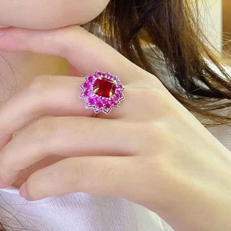 Ornate ring featuring a central red gemstone surrounded by pink stones.