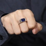 Load image into Gallery viewer, Silver ring with a rectangular blue gemstone worn on a hand.
