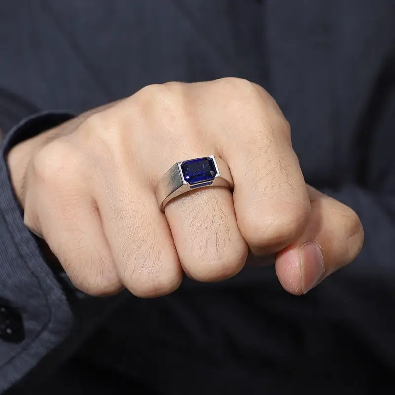 Silver ring with a rectangular blue gemstone worn on a hand.