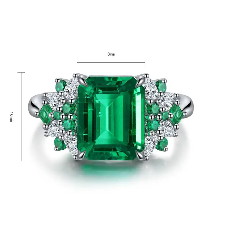 Emerald-cut green gemstone ring with diamond accents set in white metal.