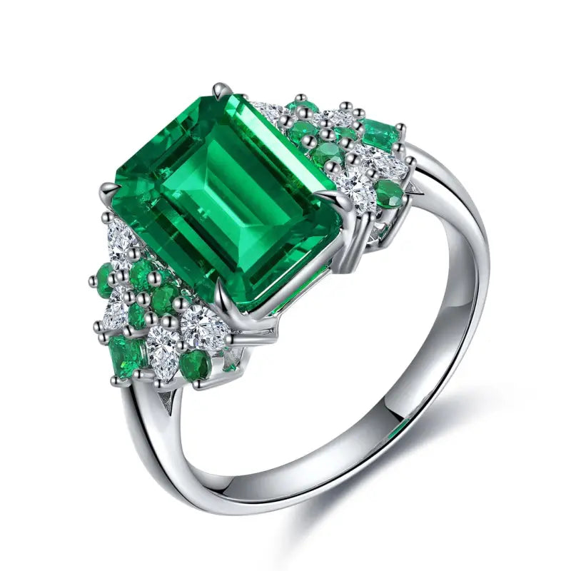 Emerald-cut green gemstone ring with diamond accents set in white metal.