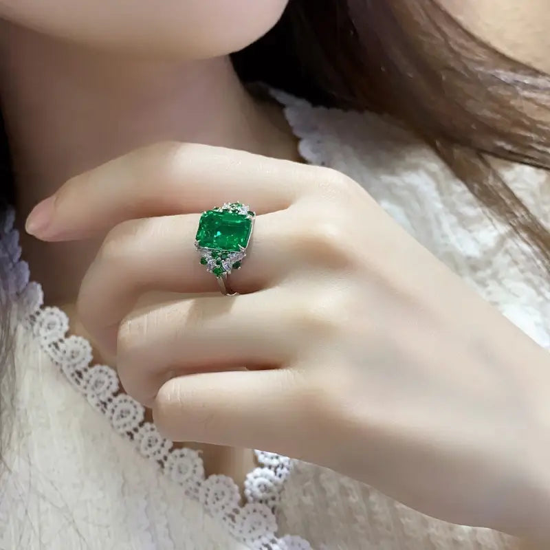 Emerald ring with a prominent green gemstone in a silver or white gold setting.